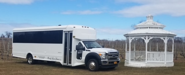 26-passenger white party bus parked next to vineyard gazebo