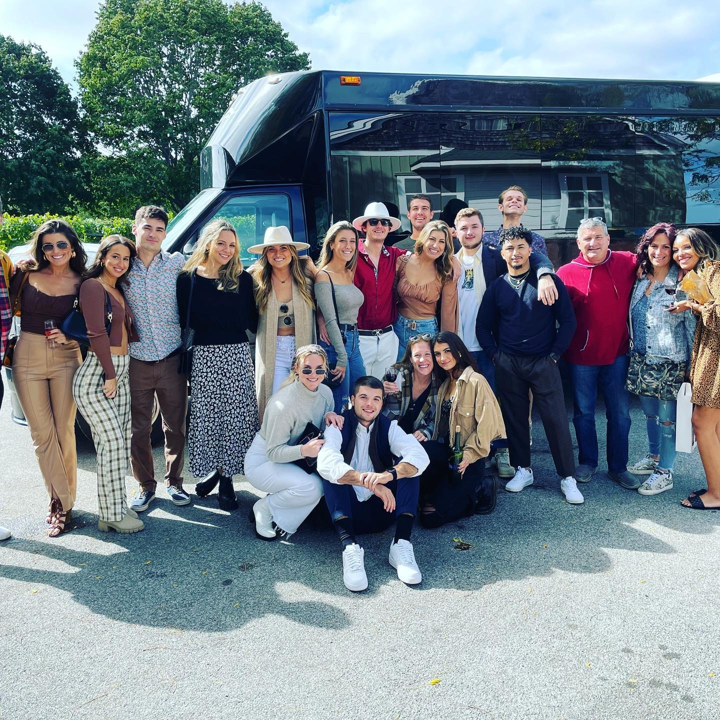 Large group posing in front of black Sprinter at vineyard