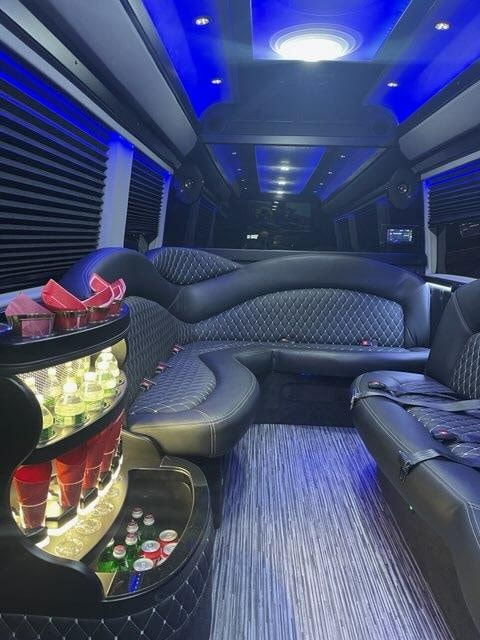 Luxury Sprinter limo interior with curved seating, bar and blue lighting